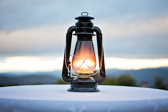 An antique gas lantern sits on a tabletop in the fading twilight.