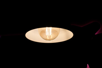 Incandescent lamp on a dark background. Reflection of light on the ceiling. Light oval.