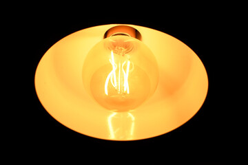 Incandescent lamp on a dark background. Reflection of light on the ceiling. Light oval.