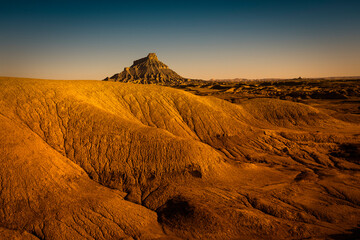 A stark desert landscape with a formation in the distance.
