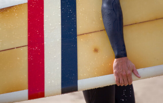 Close up of a Surfer carring colourful surf board from the beach,Cornwall,UK