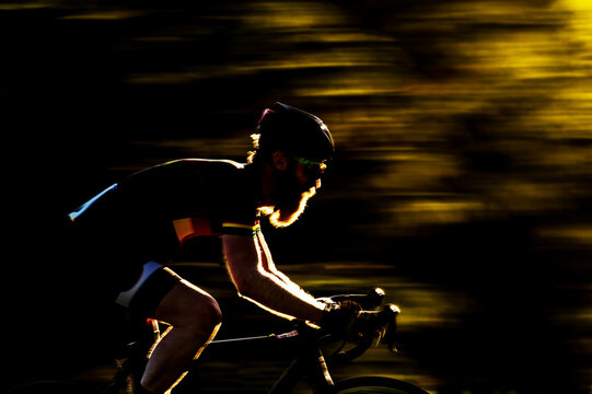 Blurred/Motion image of a bearded male cyclocross racer at speed riding through a row or trees in a race.UK.