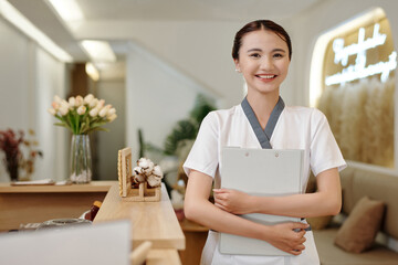 Portrait of smiling spa salon receptionist holding folder