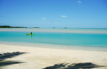Fototapeta na wymiar Kayaker paddles along in idyllic tropical lagoon