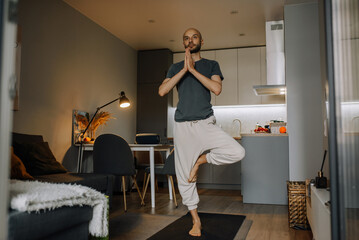 Bearded man doing yoga in his apartment