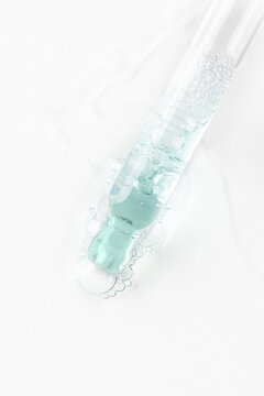 Pipette dropper and trasparent liquid smear with bubbles on white background. Serum, collagen, enzyme, peptides,hyaluronic acid swatch