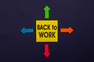 Back to work - inscription of a yellow paper note next to an four colorful arrows over a dark blue background. The concept education, training, after vacation, maternity leave, break