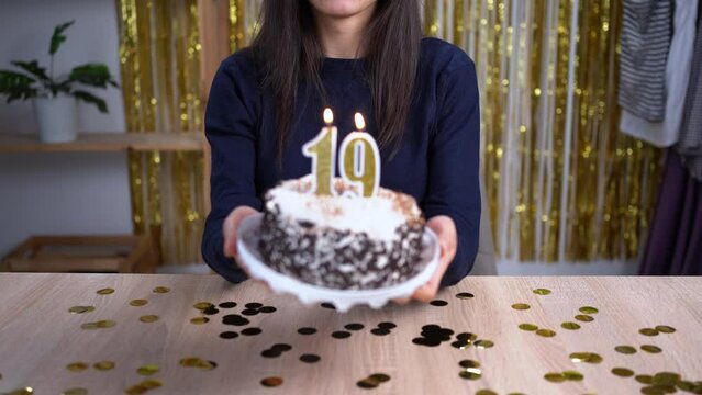 Holidays and celebration concept. Excited woman celebrating 19 birthday, blowing candle number nineteen on cake, wearing party cake and having fun on camera. Point of view or POV. Copy space