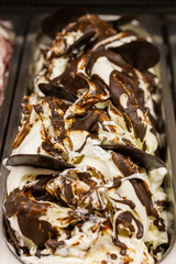 Vaschetta di gelato affogato al cioccolato fondente nella vetrina di una gelateria