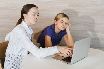 Caucasian Teacher use computer notebook teaching caucasian kid girl 