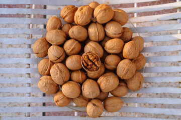 Walnut kernel on top of a pile of ripe nuts in the shell, close-up, top view, selective focus, copy space.