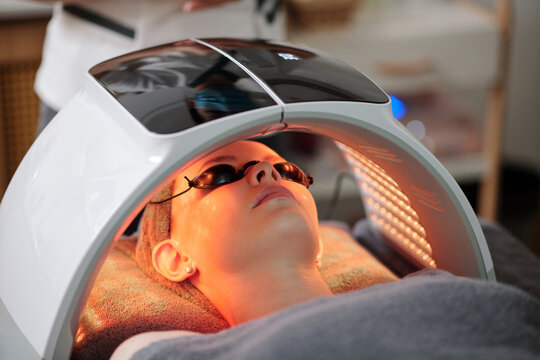 Young woman getting LED light therapy facial in beauty salon