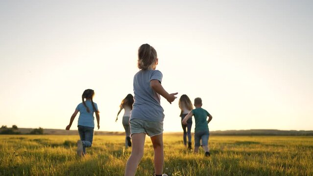 Happy family of children in summer outdoors.Children run together on grass in meadow.Silhouette of group of people playing in field.Boys and girls have fun run in the park at sunset.The Joy of Friends