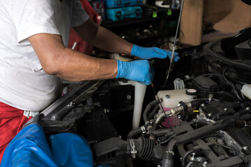 Mechanic man with rubber gloves fixing car in auto repair shop, Mechanic Concept