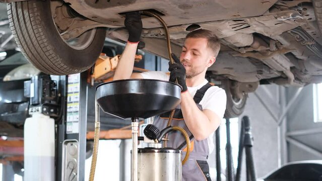 Car mechanic changing the oil in the engine of a modern car. Professional car service