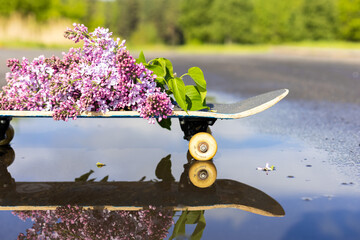 Lilac branch on a skateboard with reflection in a puddle
