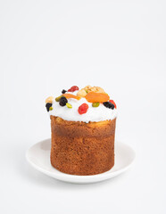 A cake with candied fruits and icing on a white plate on a white isolated background. The concept of the Easter holiday.