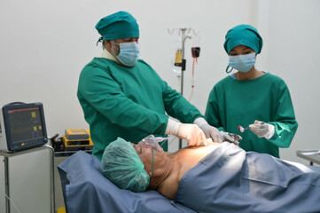 Group of surgeons and nurse in surgical green gown working at operating room of the hospital. Medical Team performing Surgical operation.