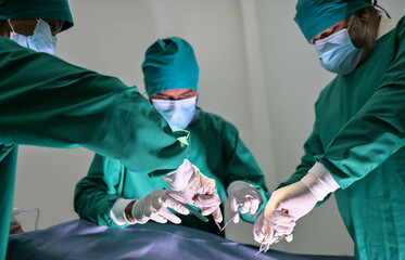 Group of surgeons and nurse in surgical green gown working at operating room of the hospital. Medical Team performing Surgical operation.
