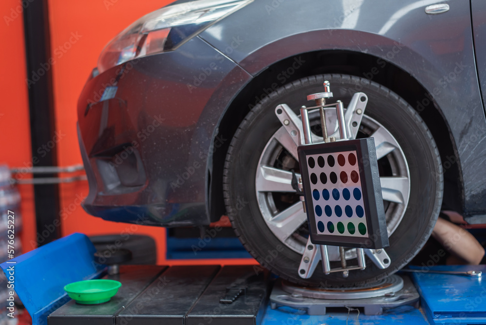Poster in the service station workshop, a car is on a stand with sensors on the wheels being checked for wh