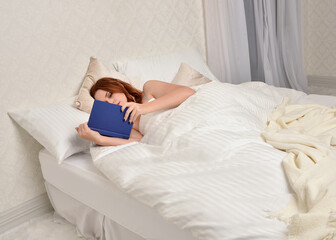 Portrait of beautiful red haired woman wearing comfortable pyjamas, casualy resting in bed, getting...