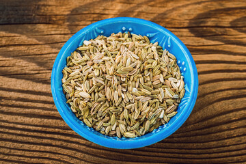 Dried fennel seeds in a bowl on a wooden board