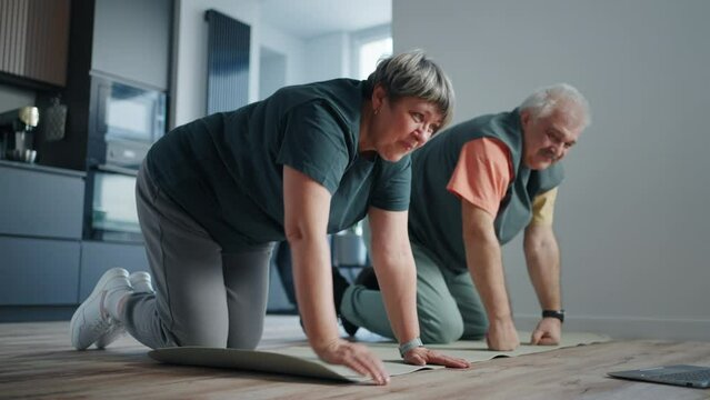 Aged Man And Woman Doing Fitness Workout At Home Together, Standing On Hands And Knees On Floor