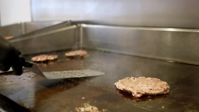 cook frying cutlets for burgers in fast food restaurant, fat unhealthy food with carcinogens