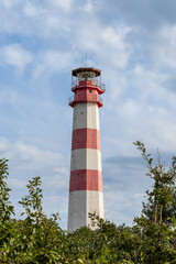 Gelendzhik. Modern lighthouse on thick cape. Multifaceted red and white column of lighthouse tower is 50 meters high against blue sky with white clouds. Close-up.