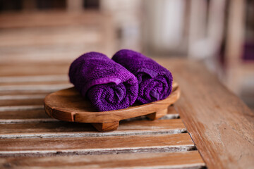 Obraz na płótnie Canvas Two purple wet towels lie on a wooden background. Cool refreshing hand towels in the restaurant.