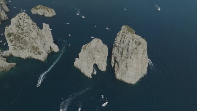 Aerial view of sailing boat cruising near the Faraglioni rock formation off Capri Island, Naples, Italy.
