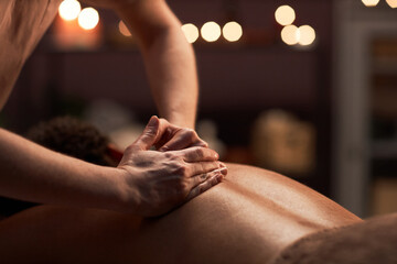 Massage therapist applying light touches when massaging back of client