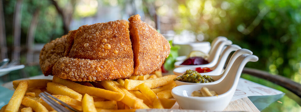 Eisbein with braised cabbage, salad and Yummy french fries with set of souces in bowl. Traditional Oktoberfest smoked pork knuckle eisbein, sauce and baked spices potato. German festival food concept.