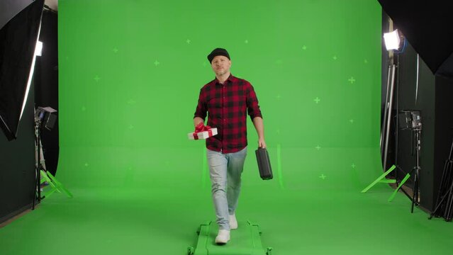 Portrait of Young Motivated Bearded Man in Shirt Holding Gift Boxes and Smiling Walking to Camera for Presenting it on a Green Screen, Chroma Key