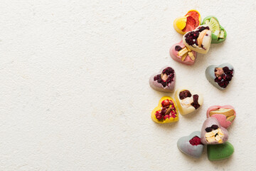 chocolate sweets in the form of a heart with fruits and nuts on a colored background. top view with space for text, holiday concept