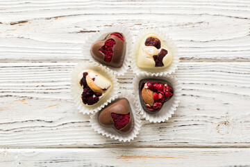 chocolate sweets in the form of a heart with fruits and nuts on a colored background. top view with space for text, holiday concept