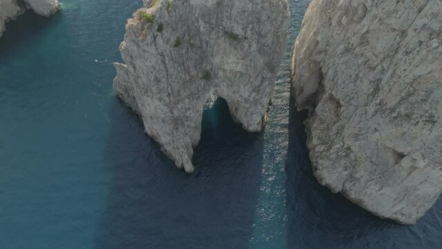 Aerial view of sailing boat cruising near the Faraglioni rock formation off Capri Island, Naples, Italy.