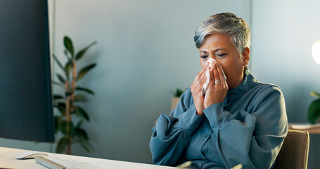 Business woman blowing her nose in the office while working on a report, document or research. Sick, professional and ill senior employee planning a corporate project or proposal in modern workplace.