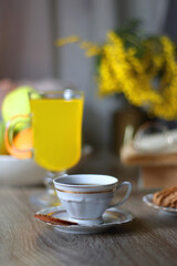 Cup of tea, plates with cookies, glass of orange juice, books, reading glasses, bowl of fruit and candles on the table. Selective focus.