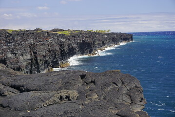 The coastal lava cliff, black contrast with blue ocean, new land made of cool lava in Big Island in Hawaii