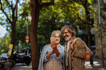Senior couple taking selfie outside.