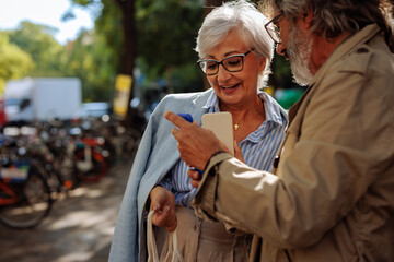 Senior friends using smartphones in street