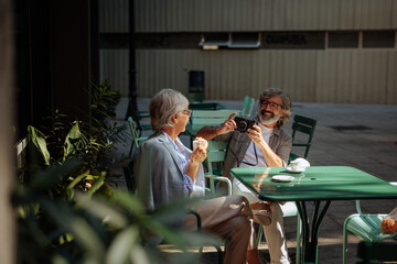 Senior couple taking pictures in cafe.