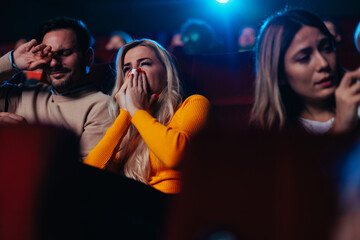 Man and woman crying in movie theater.