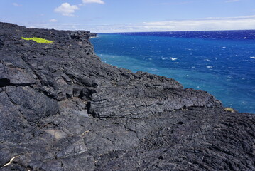 The coastal lava cliff, black contrast with blue ocean, new land made of cool lava in Big Island in Hawaii