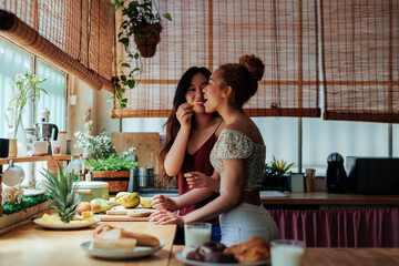 Beautiful lesbians eating fruit and having fun in the kitchen