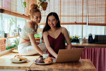 Lesbian couple using laptop at home together - Powered by Adobe