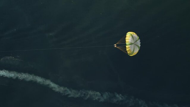 Aerial view of a person doing parasail with a motorboat along the coast in Sicily, Italy.