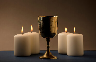 Golden Christian chalice with 4 candles with flames, brown background