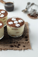 Traditional italian dessert tiramisu with savoiardi biscuits, mascarpone cheese, cream, egg yolks, amaretto liqueur and cocoa. Portion serving in glass decorated coffee beans made from powdered sugar